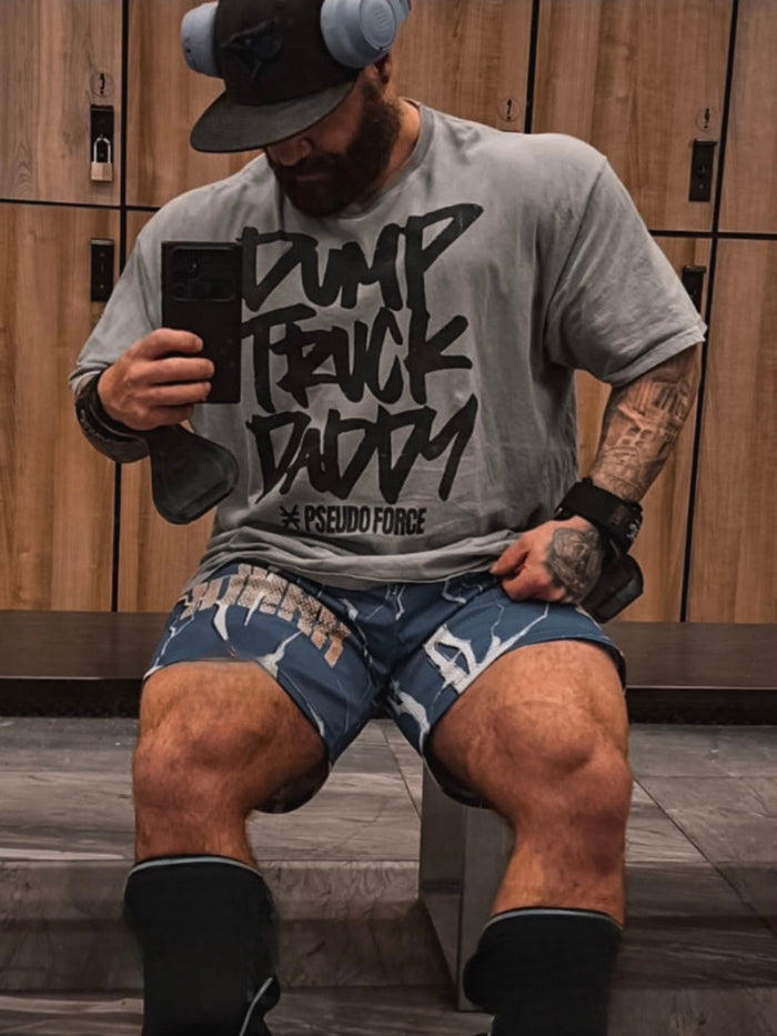 Man in locker room with gray t shirt that says “dump truck daddy” from pseudo force in black ink. 