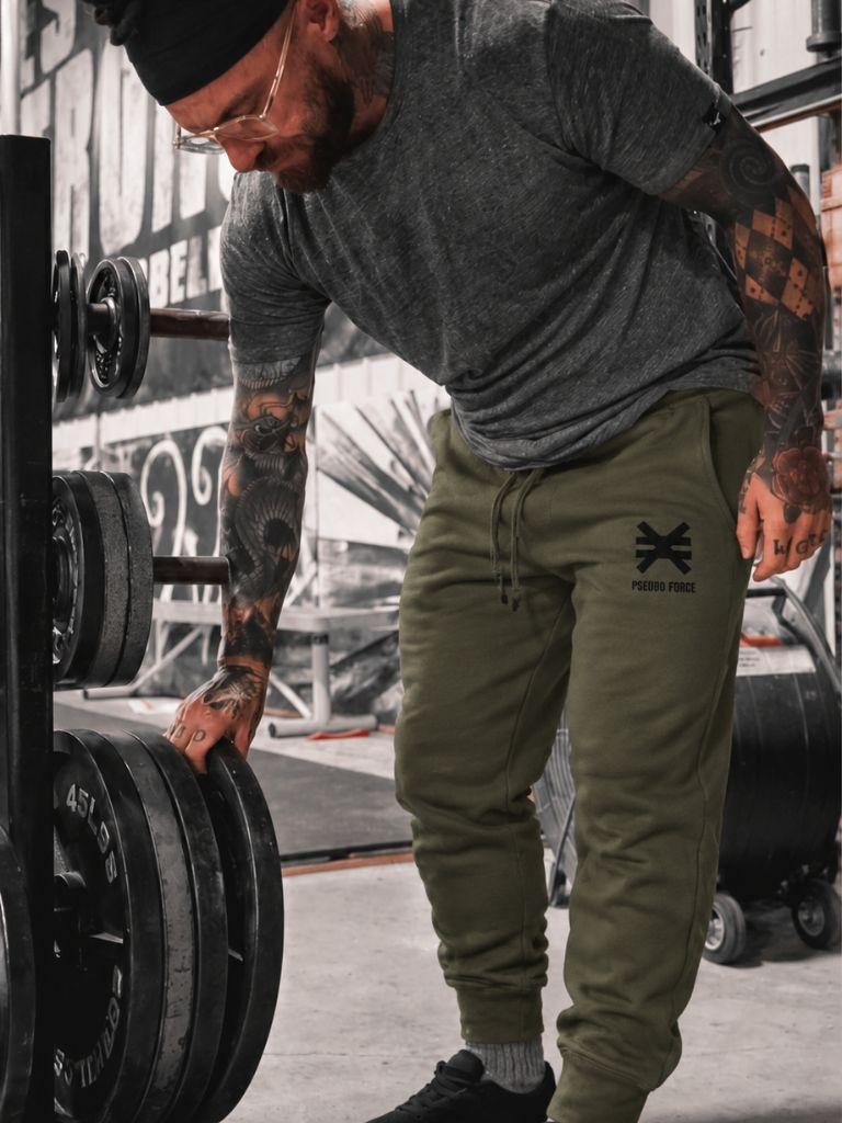 man in gym with tattoos wearing pseudo force green sweatpants