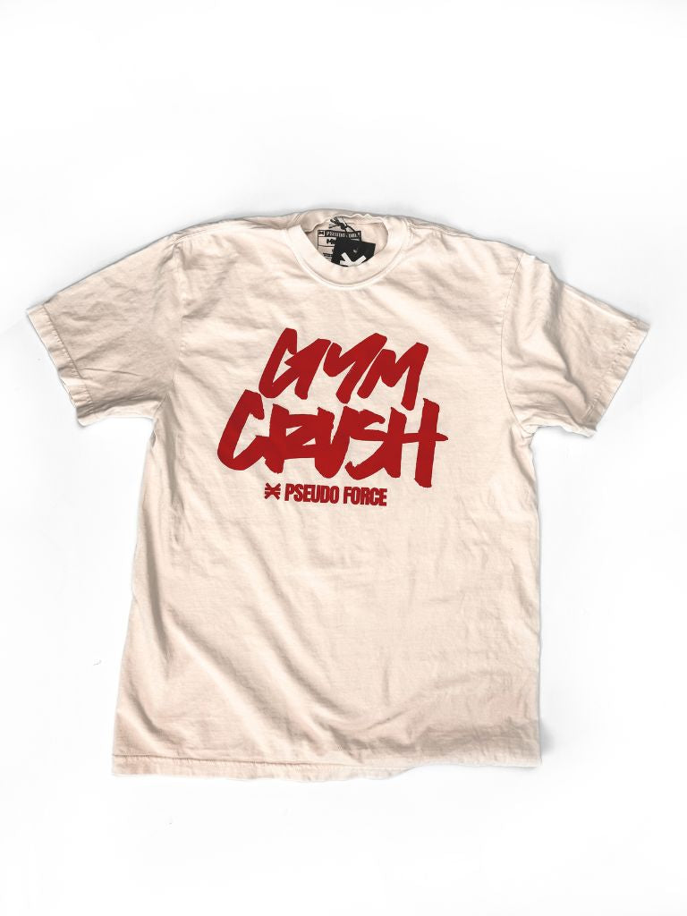Cream-colored T-shirt laid flat on a white background. Front of the shirt features red handwritten-style text reading ‘Gym Crush’ with ‘Pseudo Force’ printed below.