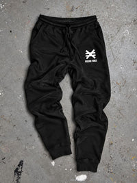 black sweatpants on cement background with white pseudo force logo on left leg near pocket.