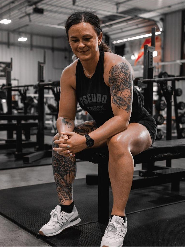 woman on bench at gym in black pseudo force tank