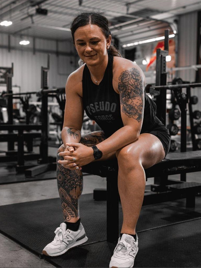 woman on bench at gym in black pseudo force tank
