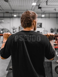 man in gym wearing a black shirt that says pseudo