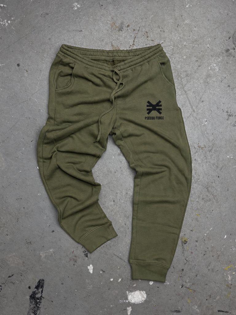 green jogger sweatpants on cement floor with ink splatters. Black Pseudo Force logo on pocket