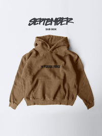 A brown hoodie with a kangaroo pocket and a black 'PSEUDO FORCE' logo on the chest, displayed flat against a light gray background with 'SEPTEMBER SUB BOX' text above.