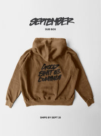 A brown hooded sweatshirt shown from the back on a light gray background, with black text reading 'GOOD SHIT IS COMING' across the back. Above the hoodie, 'SEPTEMBER SUB BOX' is printed, and below, 'SHIPS BY SEPT 25'.