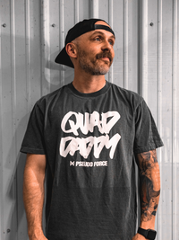 Man wearing a black t-shirt with 'Quad Daddy' in white text against a metallic wall.